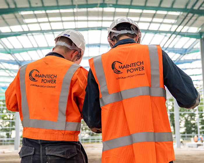 Two men in Maintech hi-vis jackets looking at plans